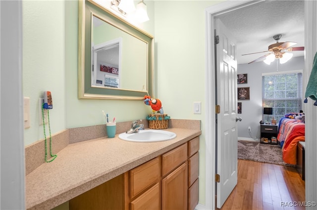 bathroom with vanity, hardwood / wood-style floors, a textured ceiling, and ceiling fan