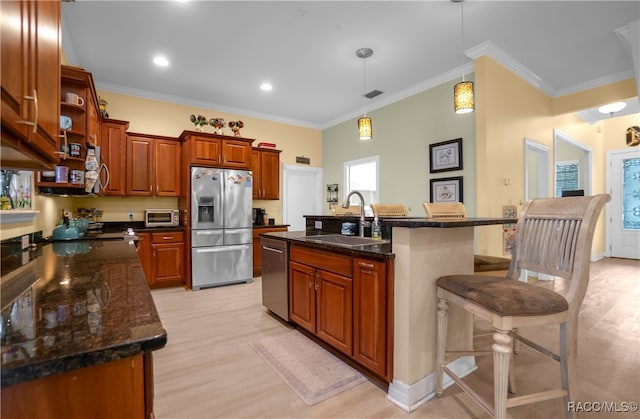 kitchen with sink, stainless steel appliances, decorative light fixtures, a kitchen island with sink, and a breakfast bar