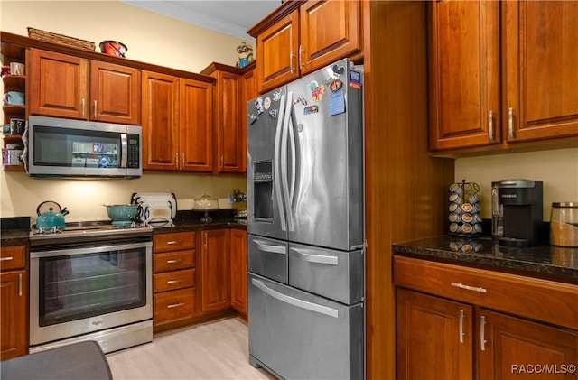 kitchen featuring dark stone countertops, light hardwood / wood-style flooring, stainless steel appliances, and ornamental molding