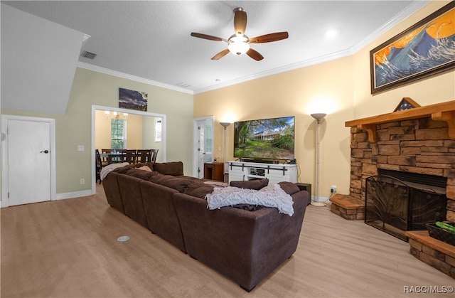 living room with ceiling fan, a stone fireplace, ornamental molding, and light hardwood / wood-style flooring