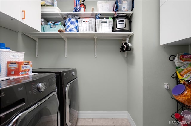 washroom with cabinets, light tile patterned floors, and washer and clothes dryer