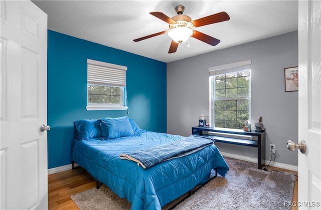 bedroom with hardwood / wood-style flooring, ceiling fan, a textured ceiling, and multiple windows