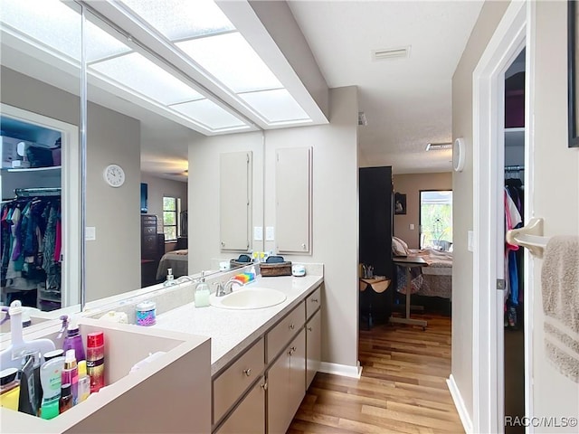 bathroom with vanity, ensuite bathroom, visible vents, a healthy amount of sunlight, and wood finished floors