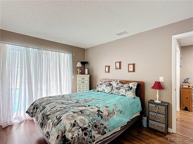 bedroom featuring a textured ceiling, wood finished floors, and visible vents