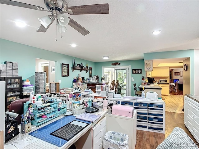 interior space with a textured ceiling, a ceiling fan, and light wood finished floors