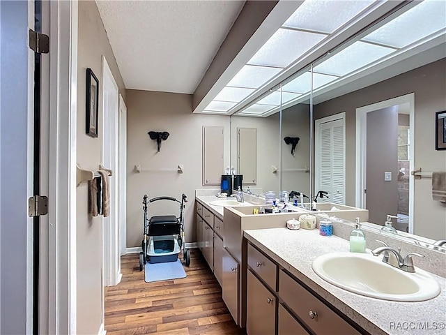 full bath with wood finished floors, vanity, and baseboards