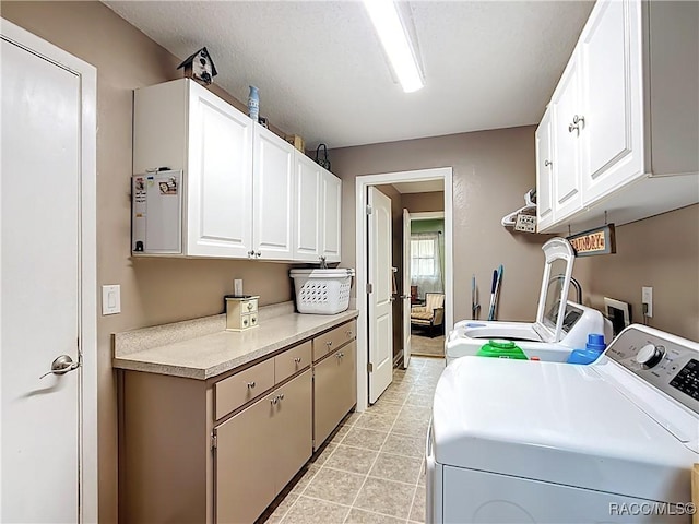 washroom with cabinet space, light tile patterned floors, and separate washer and dryer