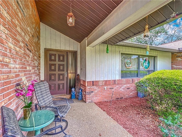 doorway to property with brick siding and a porch