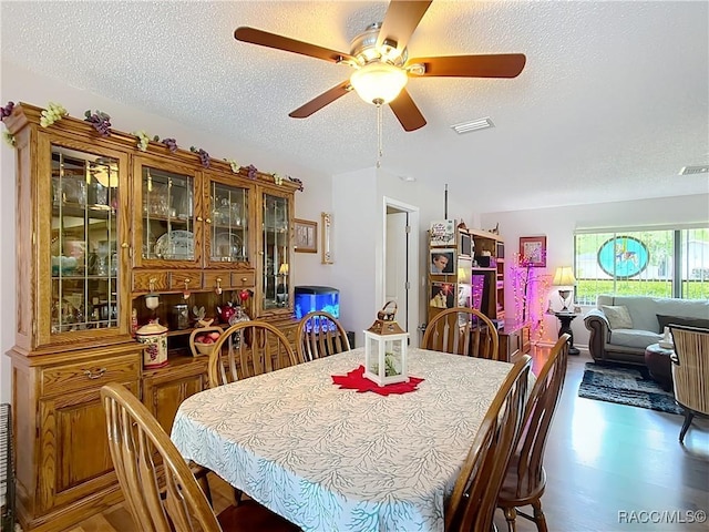 dining space featuring visible vents, a ceiling fan, and a textured ceiling