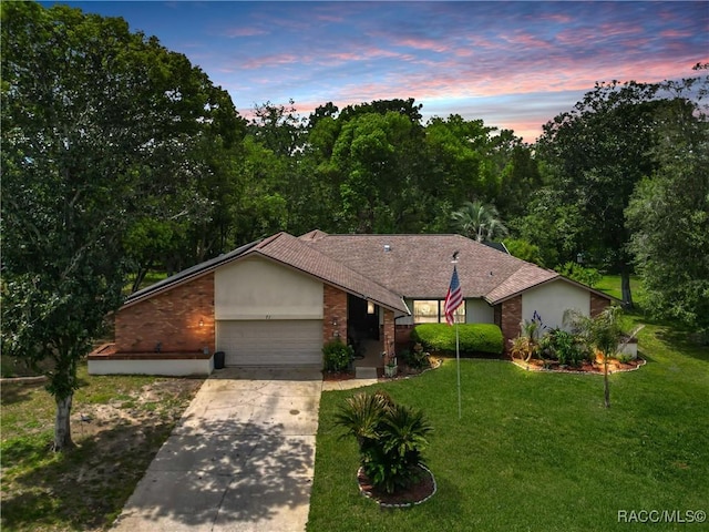 view of front of home featuring roof with shingles, a front lawn, brick siding, a garage, and concrete driveway