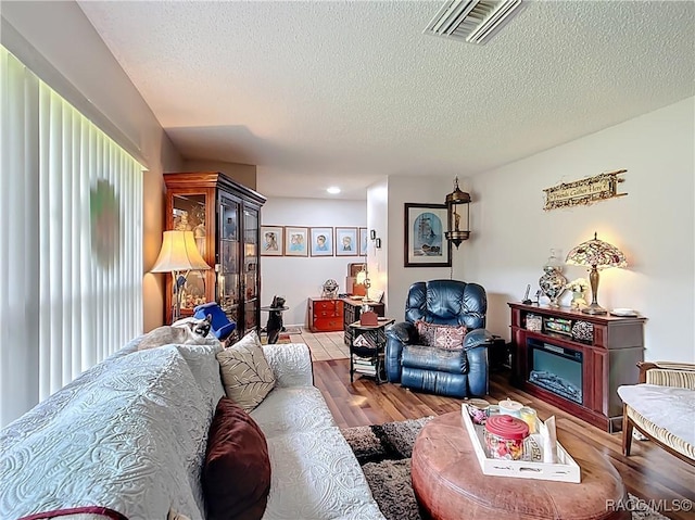living room with visible vents, a textured ceiling, and wood finished floors
