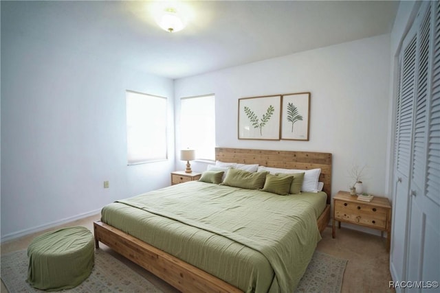 carpeted bedroom featuring a closet and baseboards