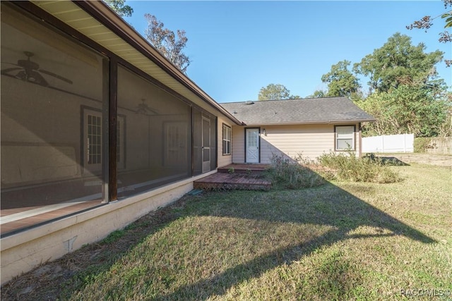 view of yard with a ceiling fan, a sunroom, and fence