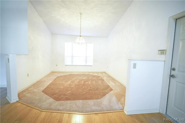 unfurnished room with baseboards, a chandelier, and wood finished floors