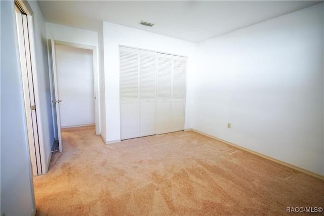 unfurnished bedroom featuring carpet floors, baseboards, a closet, and visible vents