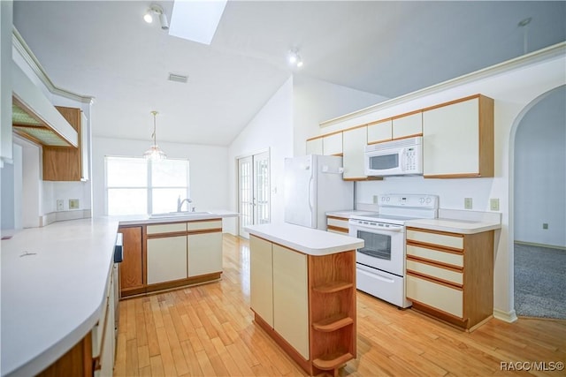 kitchen with white appliances, vaulted ceiling with skylight, light wood-style flooring, and a peninsula