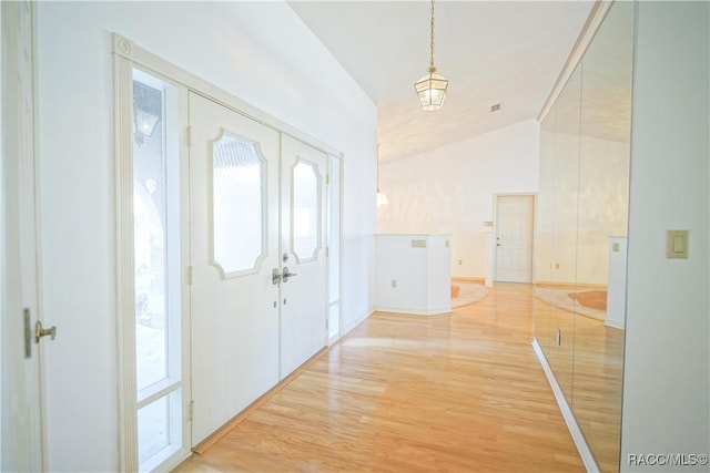 foyer with lofted ceiling, french doors, light wood-type flooring, and plenty of natural light