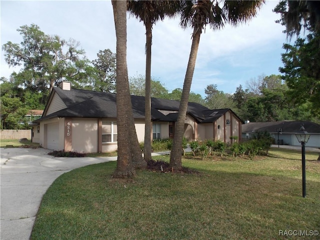 view of front of home featuring concrete driveway, fence, an attached garage, a front yard, and a chimney