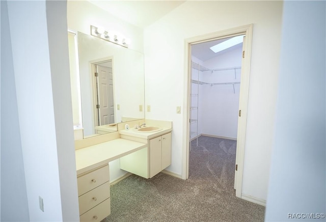 bathroom featuring carpet flooring, baseboards, a spacious closet, and vanity