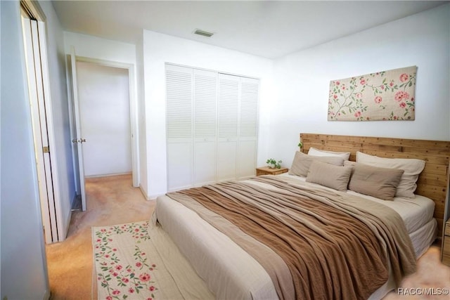 bedroom with a closet, visible vents, and light colored carpet