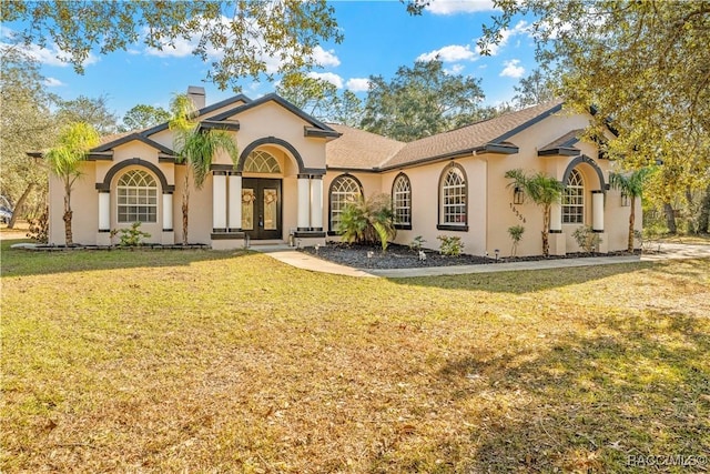 mediterranean / spanish house with a front lawn and french doors