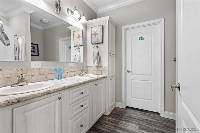 bathroom featuring ornamental molding, wood finished floors, a sink, and double vanity