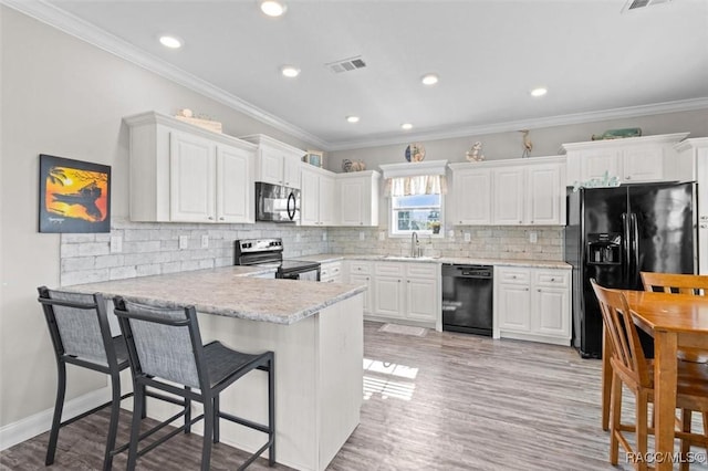 kitchen with a kitchen breakfast bar, black appliances, visible vents, and white cabinets