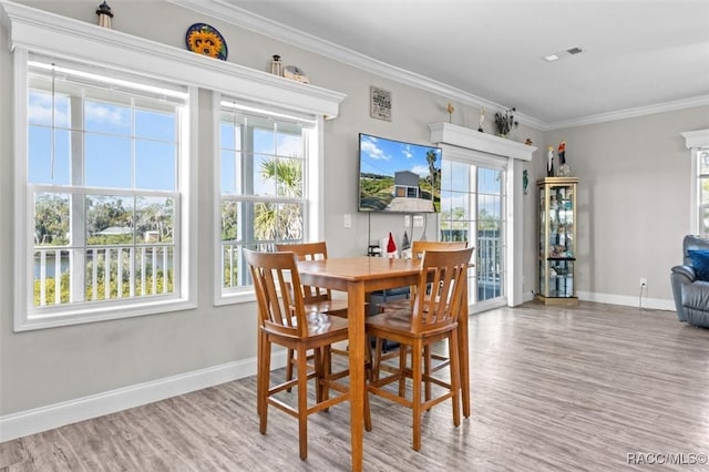 dining area with a healthy amount of sunlight, wood finished floors, visible vents, and crown molding