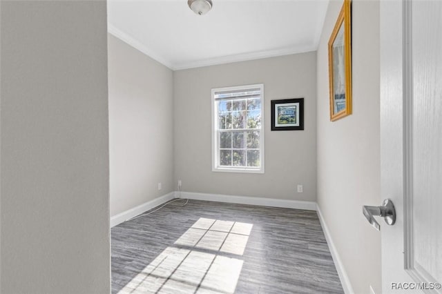 spare room featuring baseboards, ornamental molding, and dark wood-type flooring