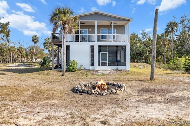 back of house featuring an outdoor fire pit, a sunroom, and a balcony