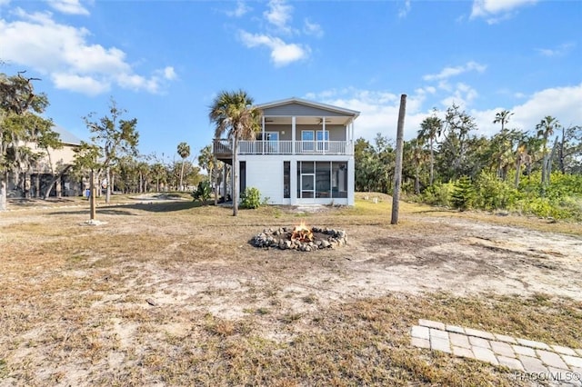 back of property with a fire pit and a balcony