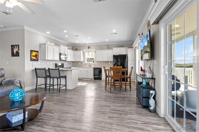 interior space featuring a ceiling fan, visible vents, crown molding, and wood finished floors