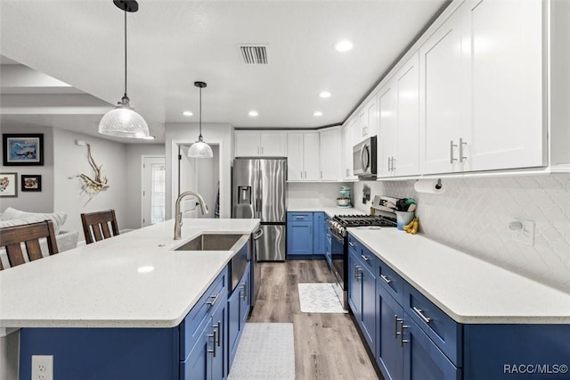 kitchen featuring pendant lighting, blue cabinets, stainless steel appliances, and light wood-type flooring