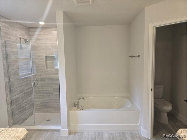 bathroom featuring a garden tub, toilet, a stall shower, wood finished floors, and baseboards