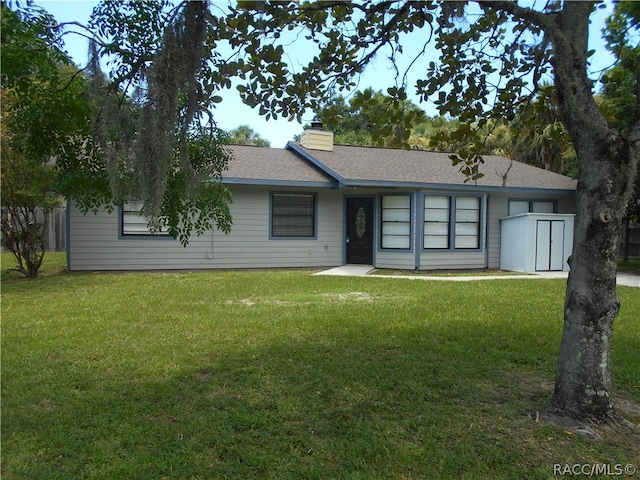 single story home with a front yard and a storage shed