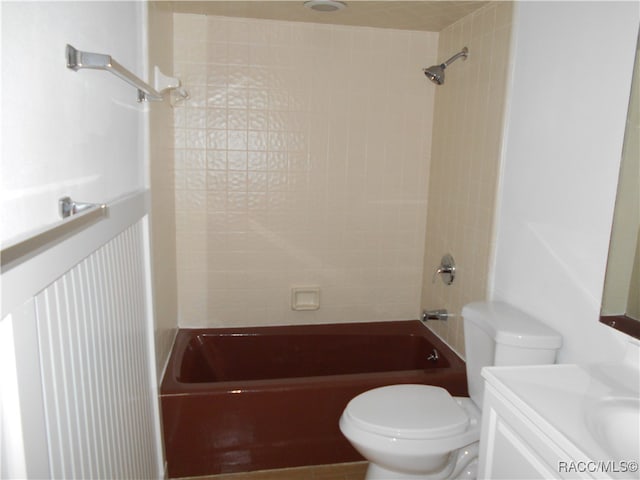 full bathroom featuring tiled shower / bath combo, toilet, and vanity