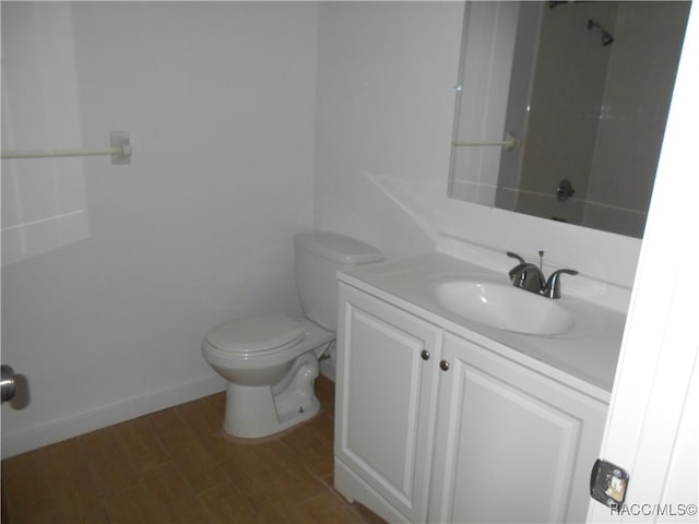 bathroom with hardwood / wood-style floors, vanity, toilet, and walk in shower