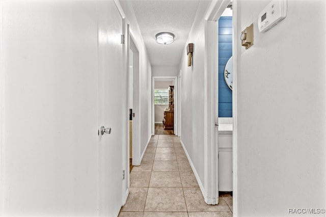 hallway featuring light tile patterned floors and a textured ceiling