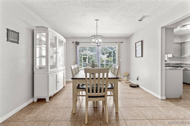 tiled dining area featuring a textured ceiling and an inviting chandelier