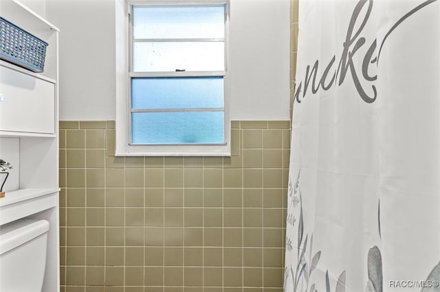 bathroom with a shower with curtain, tile walls, and toilet