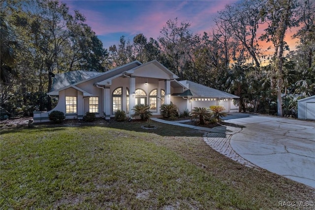 view of front facade featuring a garage, a lawn, driveway, and stucco siding