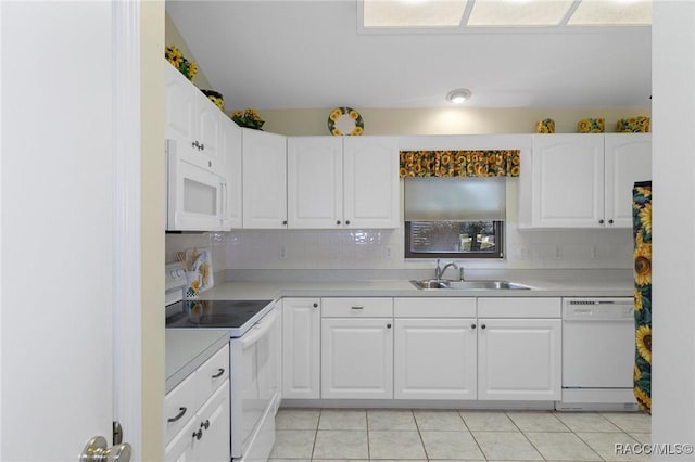 kitchen featuring decorative backsplash, white appliances, sink, light tile patterned floors, and white cabinets