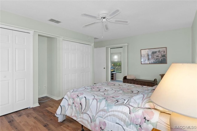 bedroom featuring multiple closets, ceiling fan, and dark hardwood / wood-style flooring