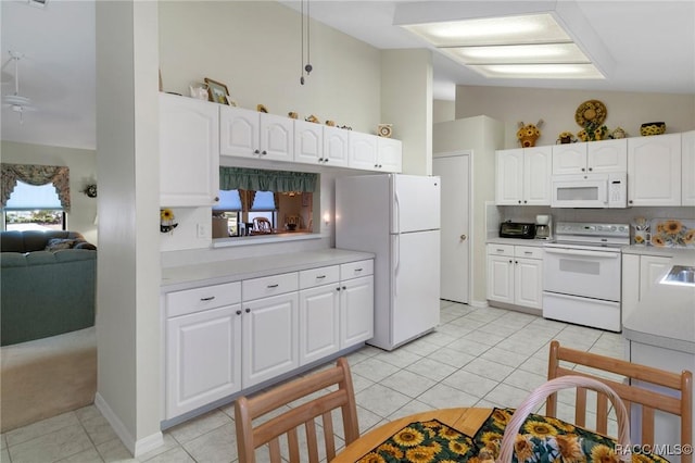 kitchen featuring lofted ceiling, white cabinetry, white appliances, and light tile patterned floors