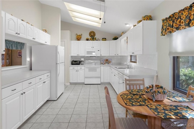 kitchen with white cabinetry, sink, lofted ceiling with skylight, white appliances, and light tile patterned floors