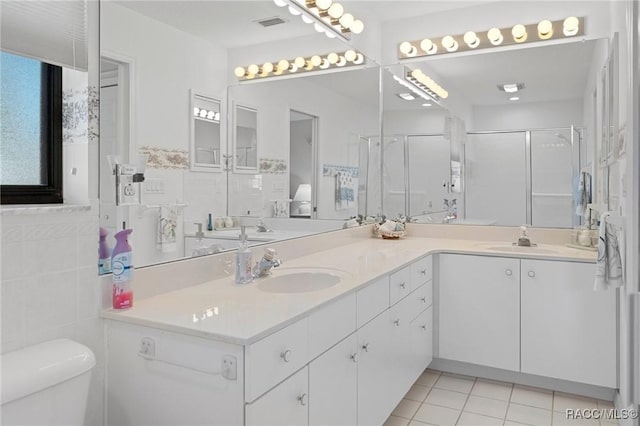 bathroom featuring tile patterned floors, an enclosed shower, toilet, vanity, and tile walls