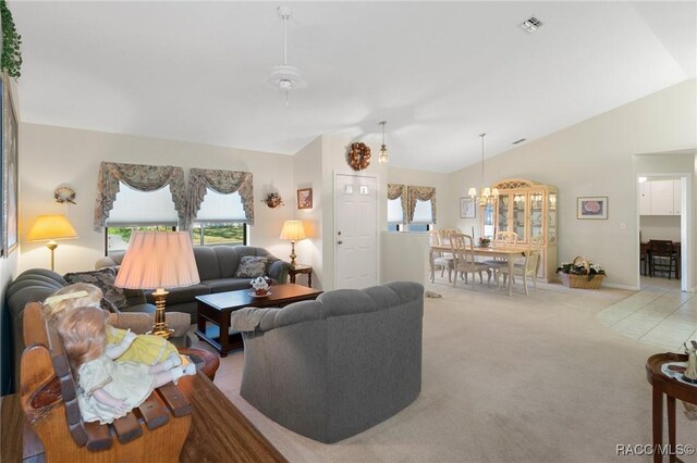 living room featuring ceiling fan with notable chandelier, light colored carpet, and lofted ceiling