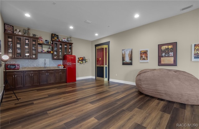 bar with indoor wet bar, visible vents, decorative backsplash, dark wood-type flooring, and a sink