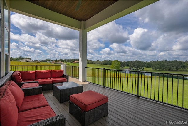 wooden terrace featuring an outdoor living space, a lawn, and a rural view