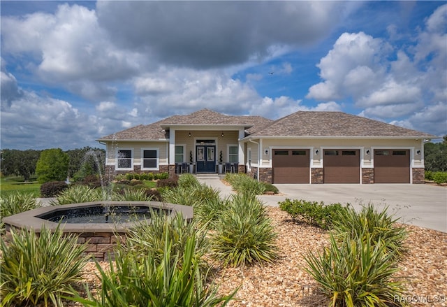 prairie-style house with an attached garage, stone siding, and driveway